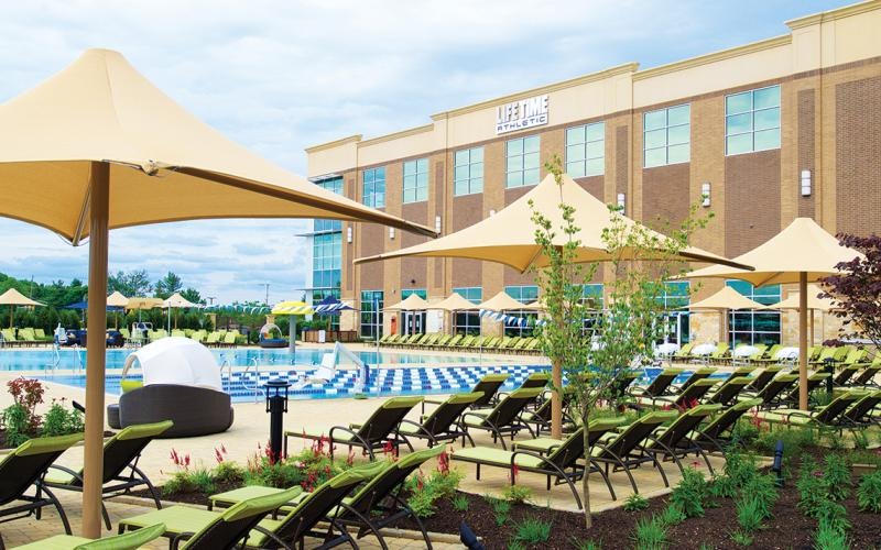 a swimming pool with chairs and umbrellas in front of a building